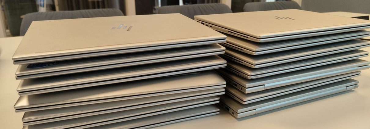 Ominstallation av 14 laptops till nya användare i Stadshagen 1 Fjorton HP EliteBook-laptops i två staplar på ett konferensbord efter ominstallation hos företag i Stadshagen