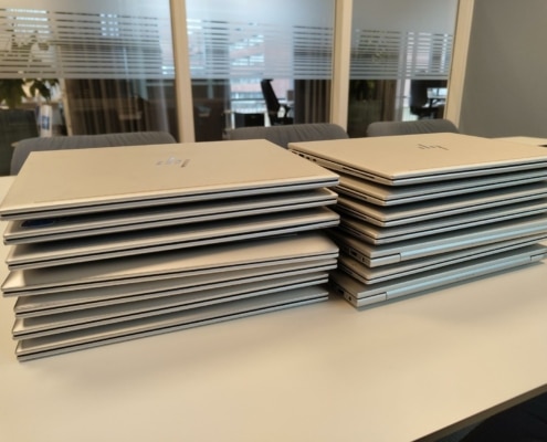 Ominstallation av 14 laptops till nya användare i Stadshagen 8 Fjorton HP EliteBook-laptops i två staplar på ett konferensbord efter ominstallation hos företag i Stadshagen